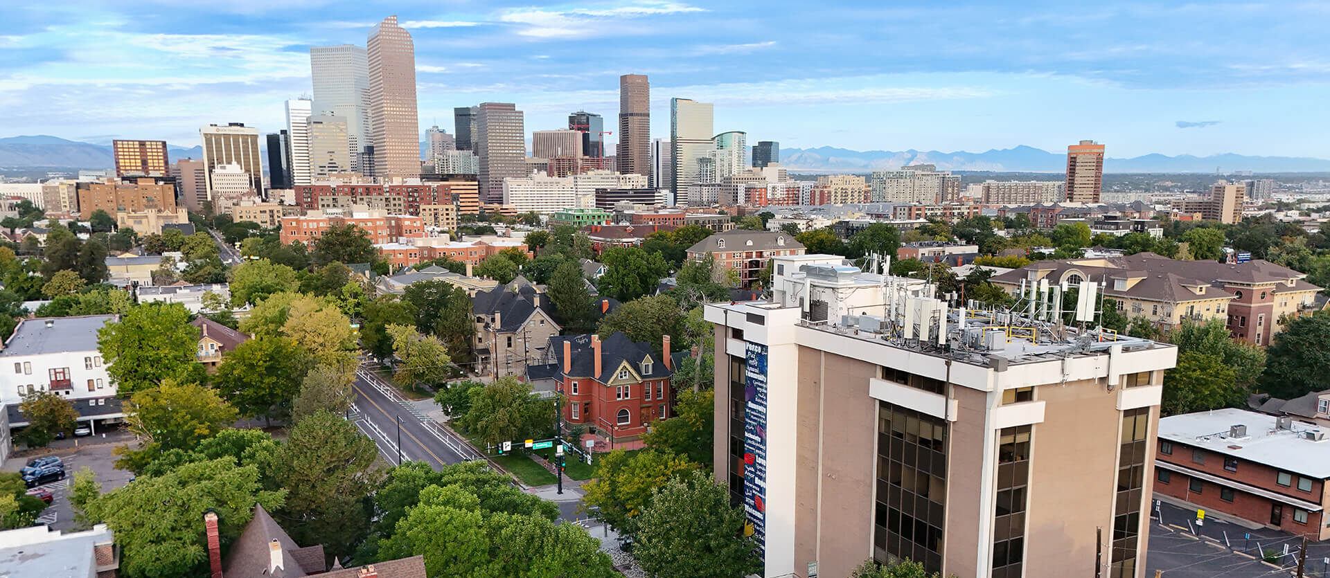 Aerial view of city street with trees and buildings, mountain horizon in the distance