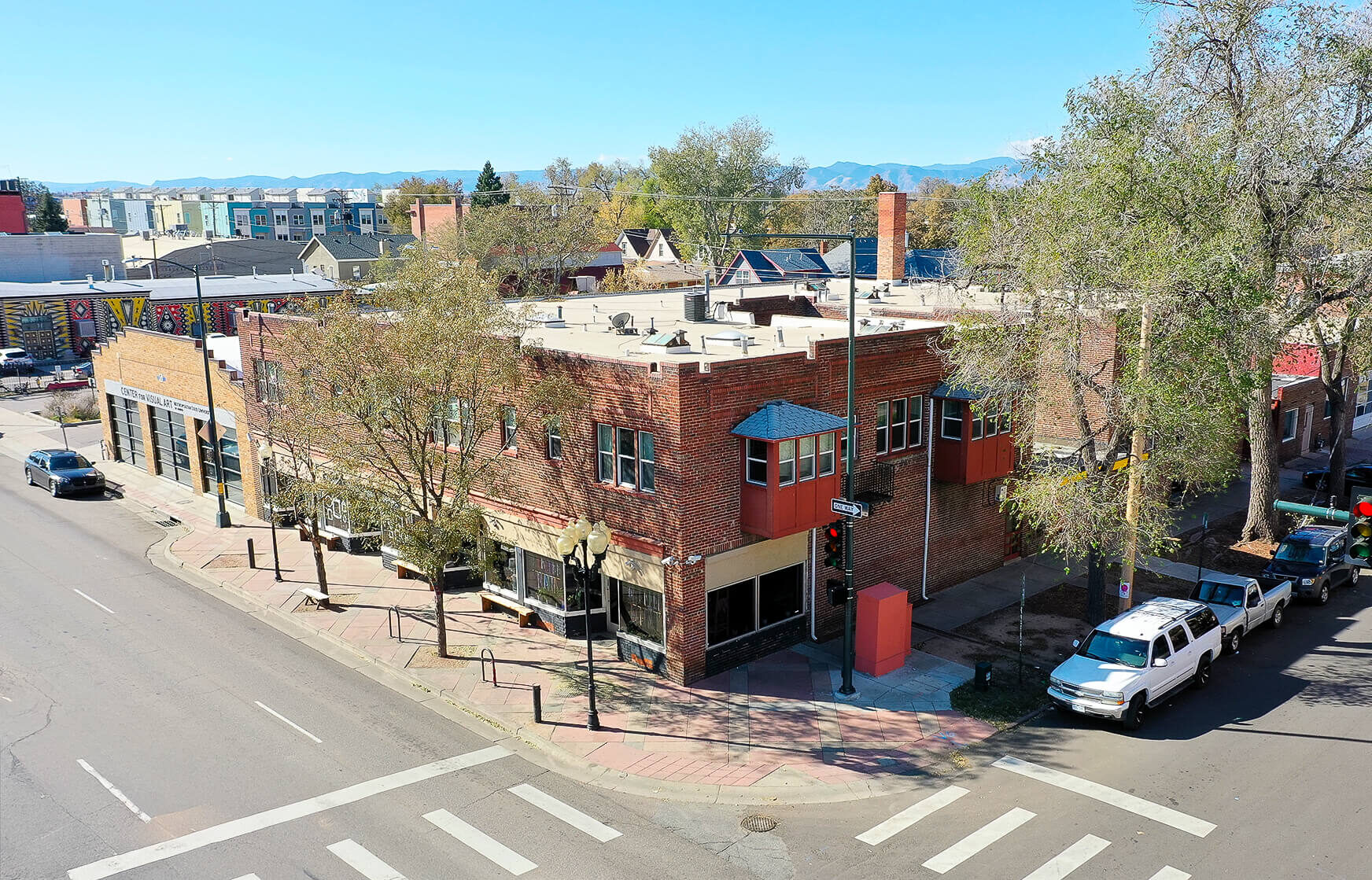 Two-story brick building on a corner lined with trees