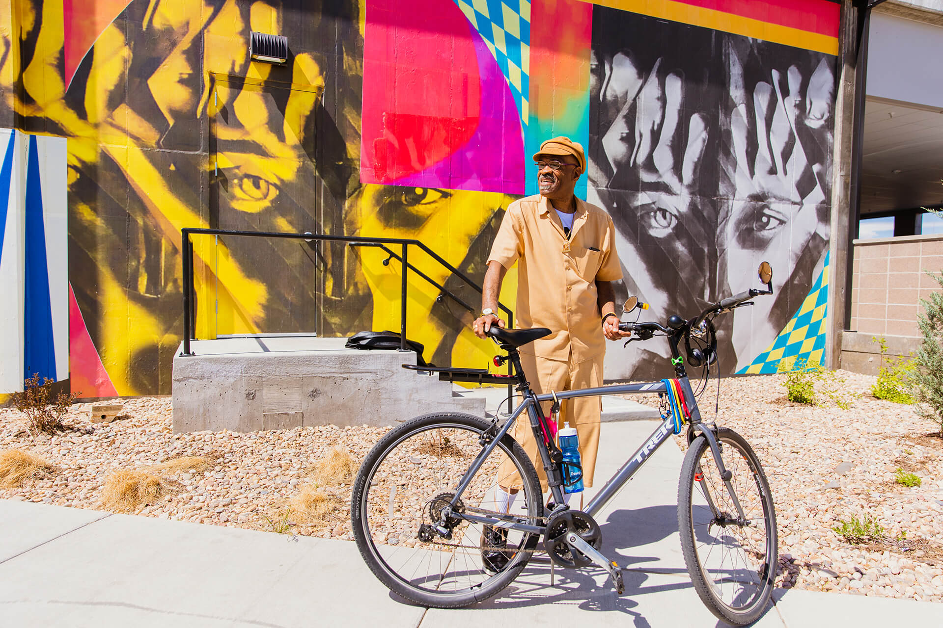 man with bicycle in front of colorful wall art