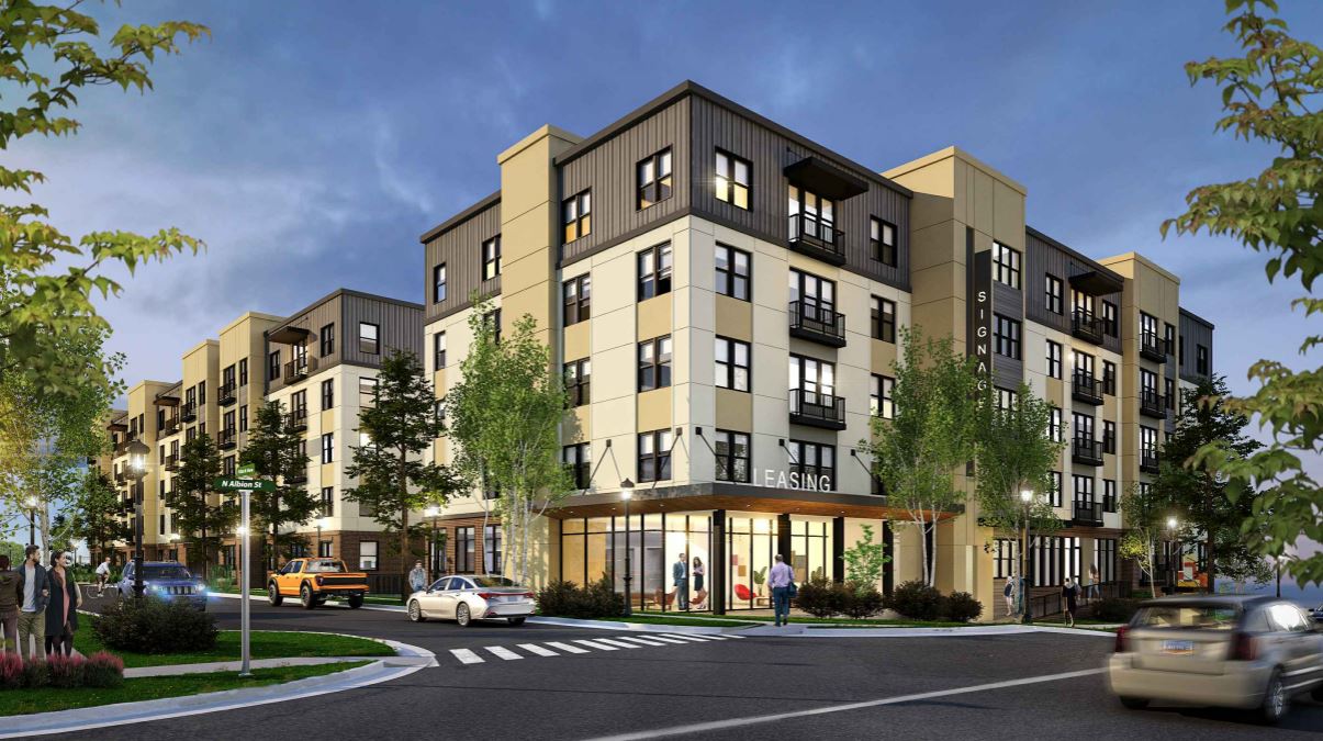 Rendering of a modern, multi-story affordable housing development at dusk with “LEASING” signage, located at the intersection of N Albion St and a residential road, surrounded by trees, cars, and pedestrians.