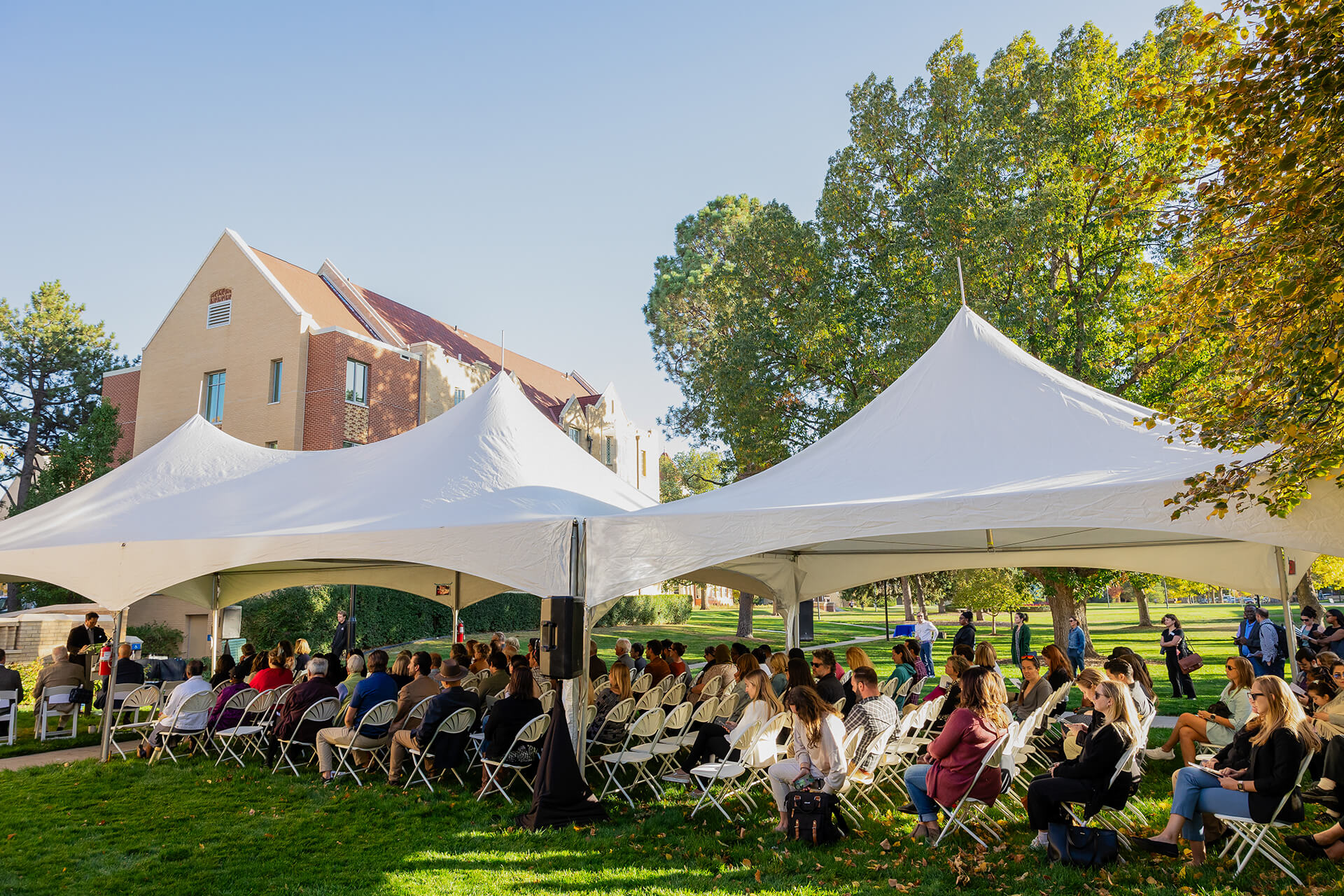 people in chairs under large tents