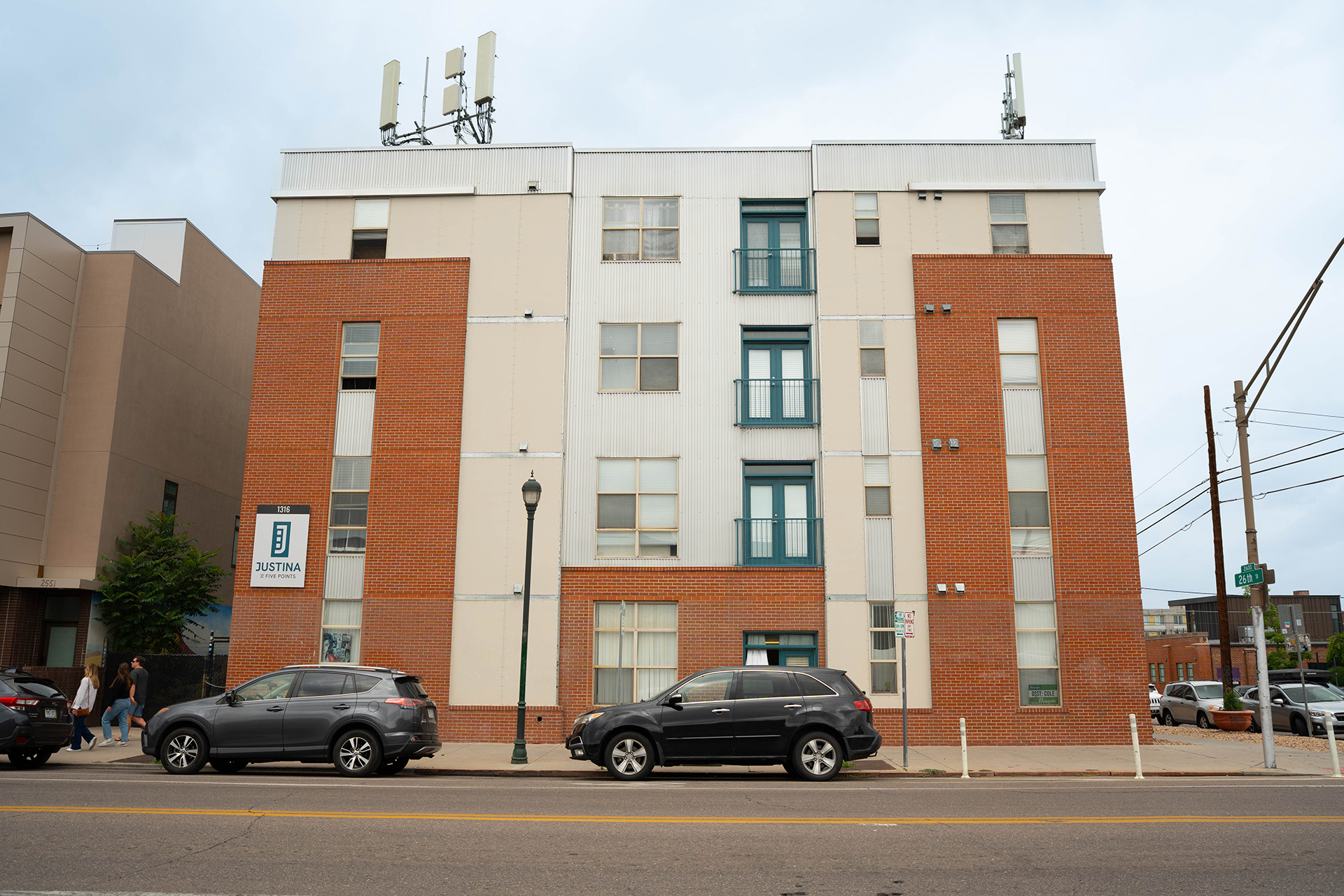 a multifamily brick apartment building with a sign that says Justina at Five Points