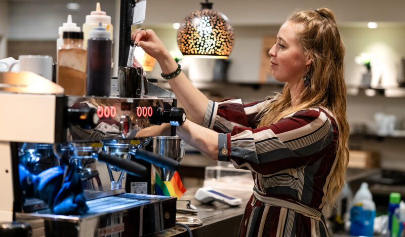 a woman pulls espresso in a coffee shop
