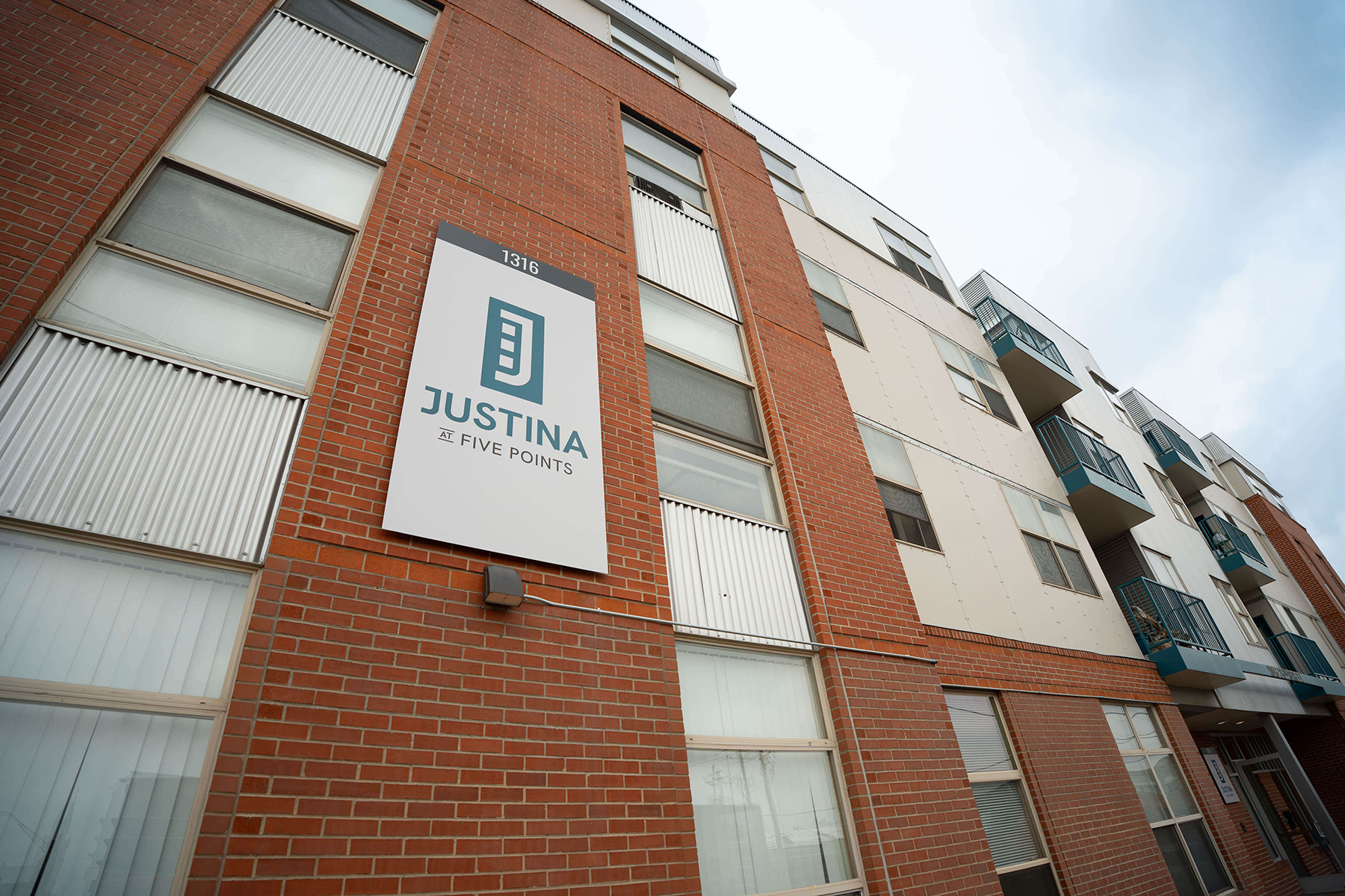 a multifamily apartment building with a sign that says Justina at Five Points